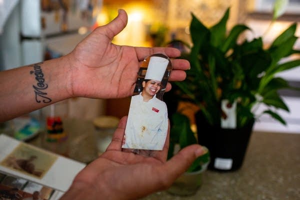 A person holds a photo of herself in culinary attire.