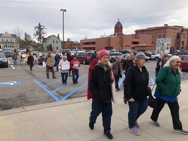 A group of people walk in a line while holding signs.