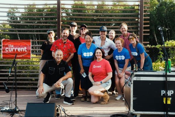 Twelve people pose for a photo together at an outdoor music event