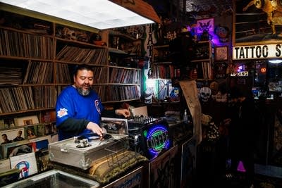 A record store proprietor plays a record on a turntable inside his shop