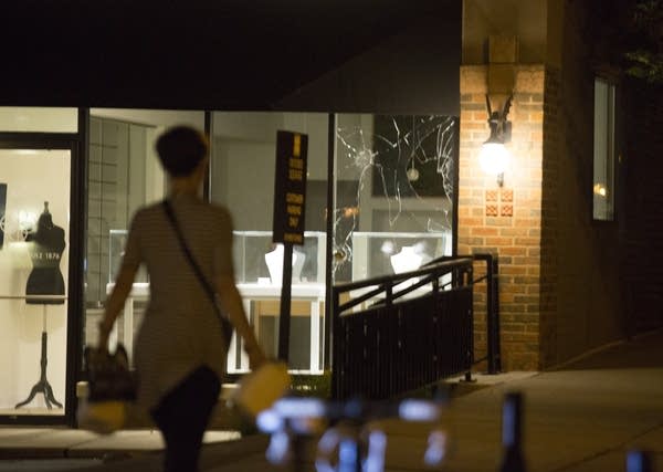 A protester stands in front of a shop window.