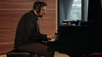 A musician plays piano in a recording studio