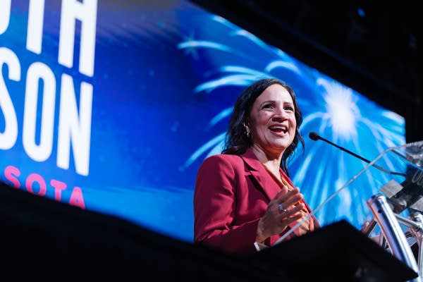 A woman speaks at a podium on stage.