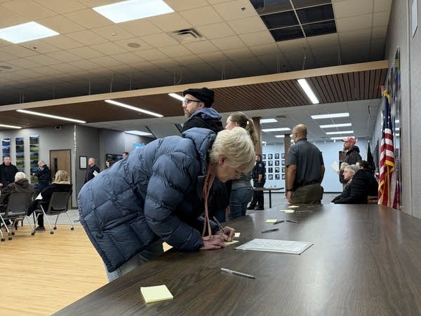 A woman writes a note on a table