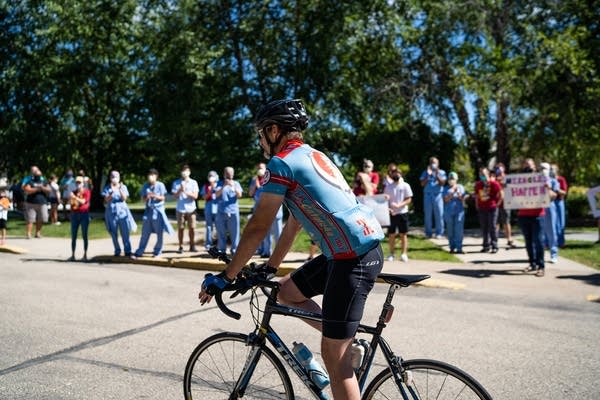 A man on a bike rides past a line of people.