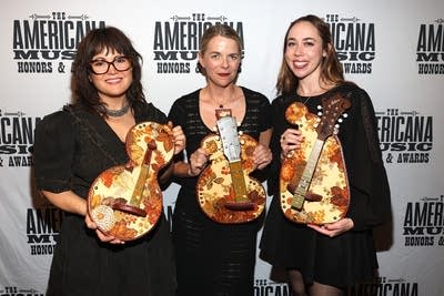 Three women hold awards