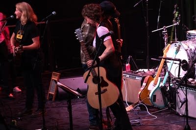 Musicians hug onstage.