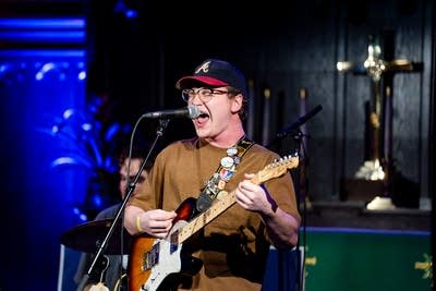 a guitarist singing and playing on stage