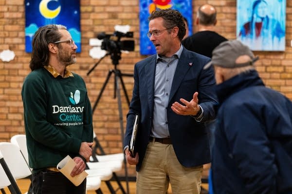 Two people stand and talk after a forum ends.