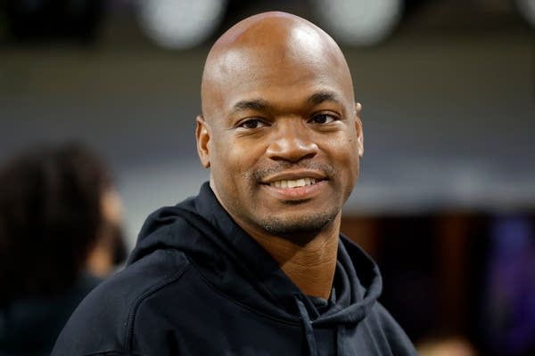 A man in a black hoodie smiles for a photo.
