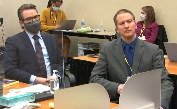 Two men sit in a courtroom.