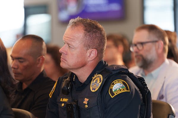 A police officer leans forward in his chair, seen from the side.
