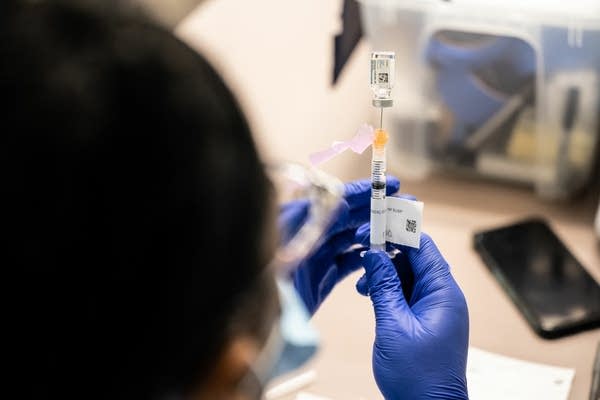 A nurse fills a syringe with a vaccine. 