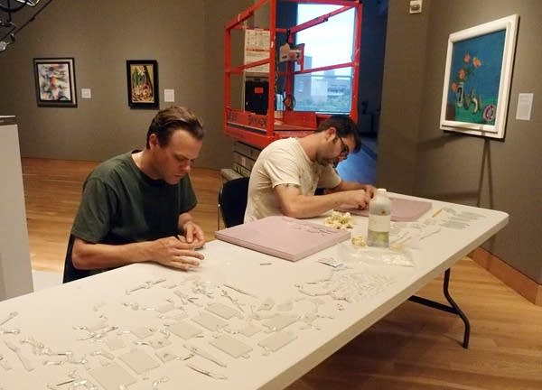 Two assistants clean some of the hundreds of glass pieces.