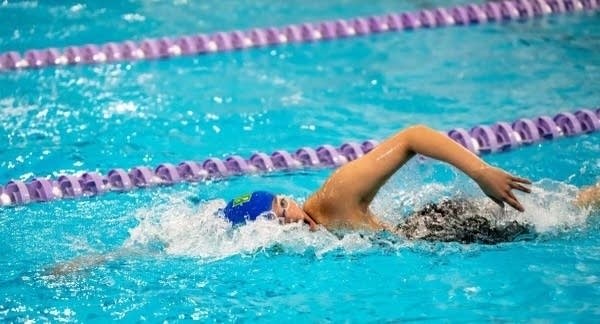 A student races in a swim meet.