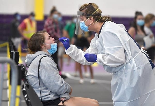 A young woman sits while being tested for COVID-19.