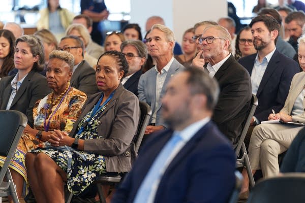 A seated crowd watches a speech.