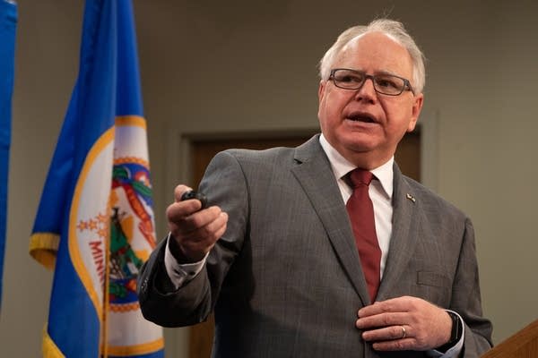 A man gestures as he speaks at a podium.