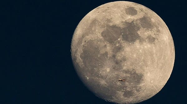 A plane flies past the moon at sunset on March 3, 2015, in London.