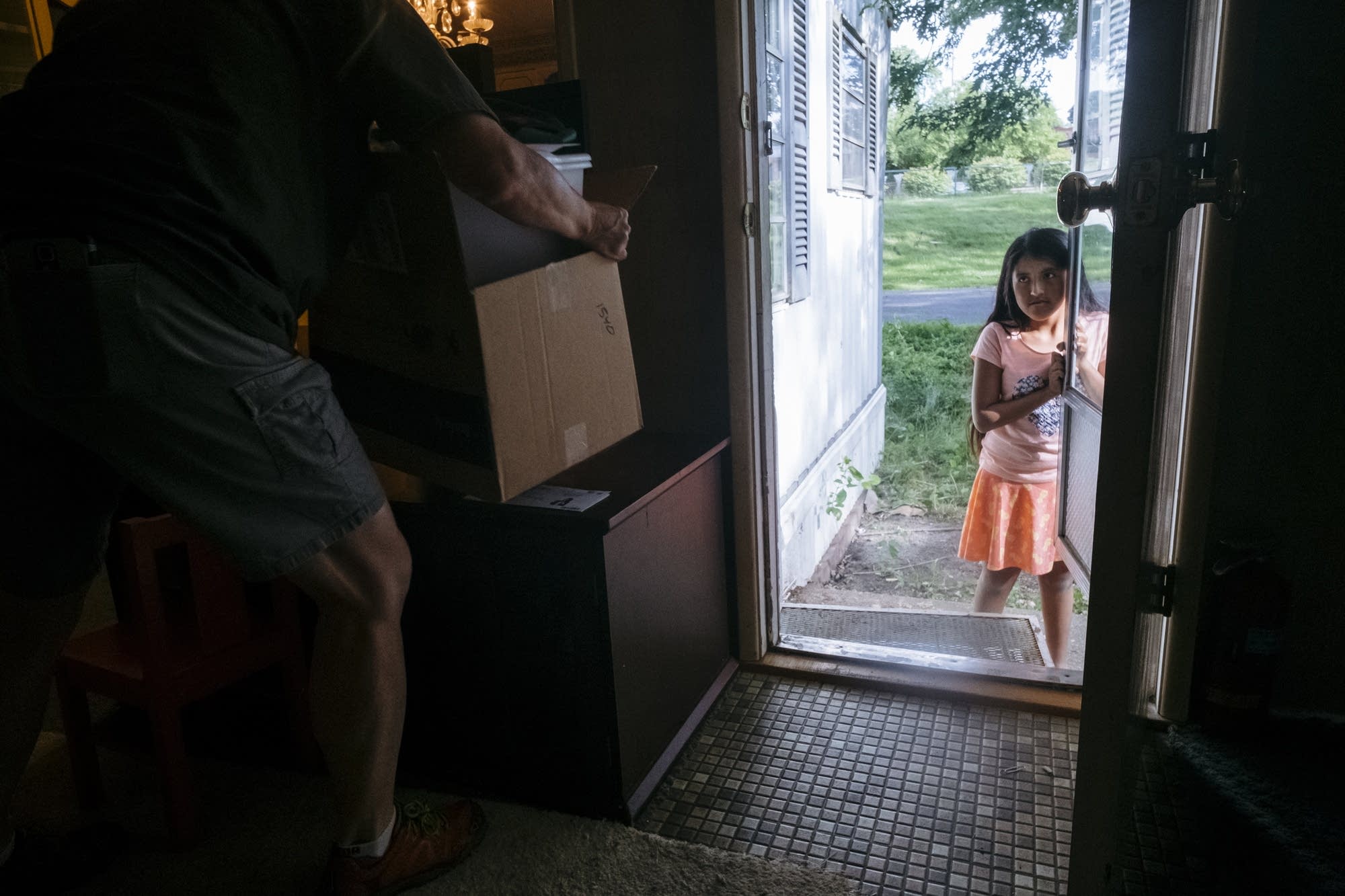 Eleven-year-old Ydira Sanchez holds the door of her mobile home.