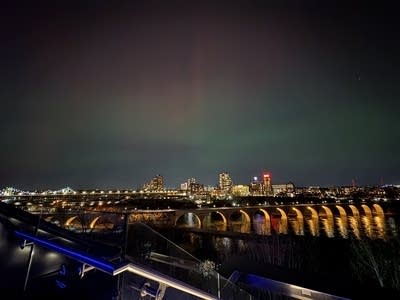 A city night scene with a view of green, red and purple lights in the sky.