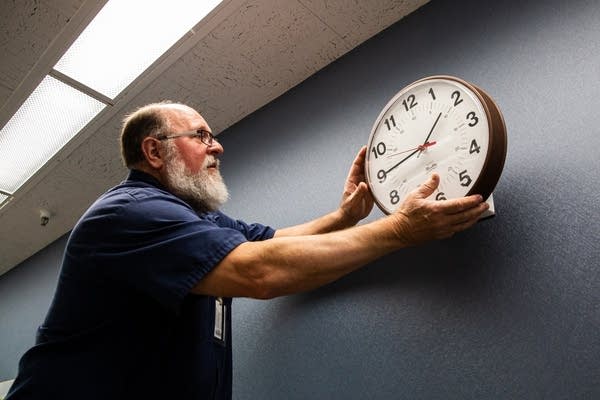 A man takes a clock off of a wall.