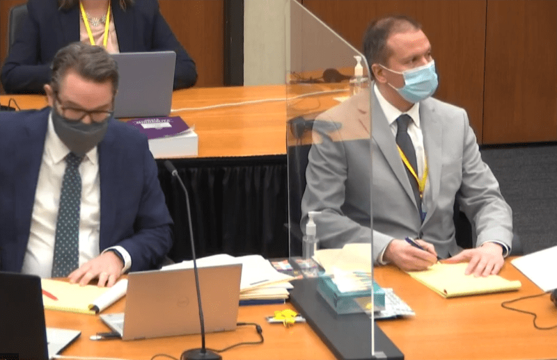 Two people listen to a judge during a trial.