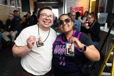 Two friends pose for a photo together at a concert in a small music venue