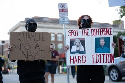 People hold signs against Charlie Kirk and his wife