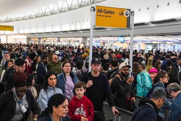 A massive crowd of people waits in line inside an airport.