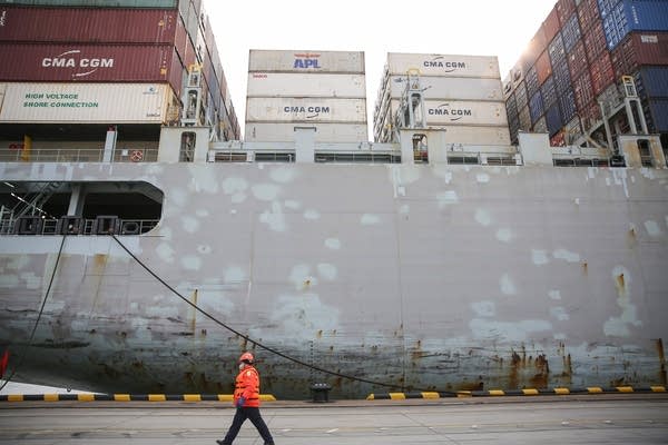 A Chinese employee wearing a protective facemask walks past a cargo ship at a port in Qingdao in China's eastern Shandong province.