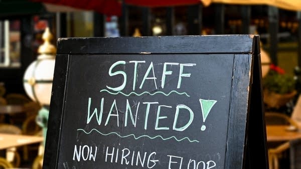 A staff wanted sign on a chalkboard outside a restaurant
