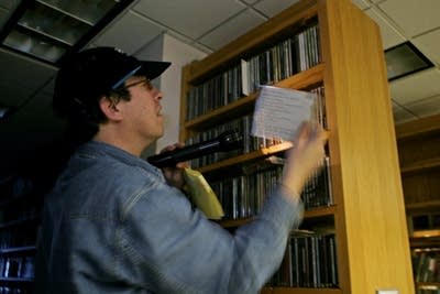 A man uses a flashlight to read the notes on a CD