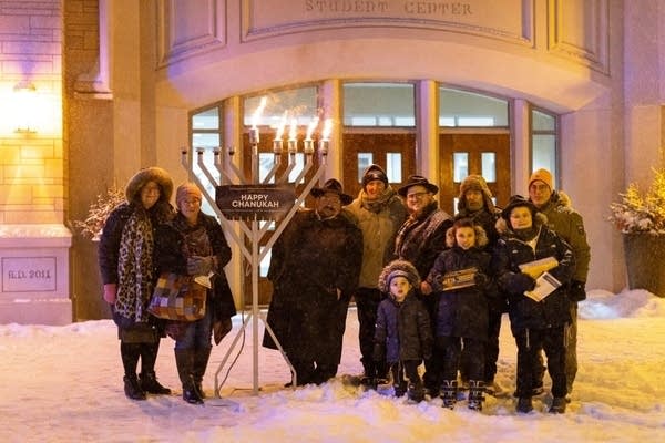 People pose in front of menorah