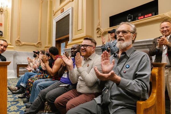 Multiple people clapping at city council meeting