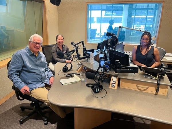 three people smiling in a broadcast studio