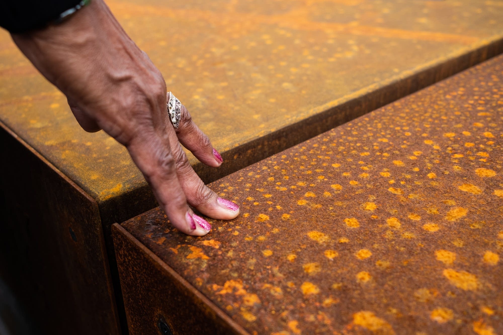 Virginia Huston rests her hand on a steel column.