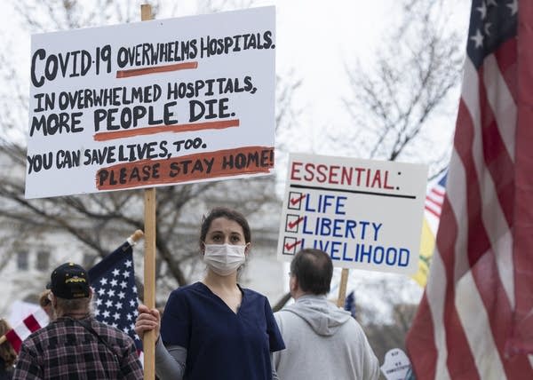 Nurse protesting in favor of business closures is surrounded by protesters