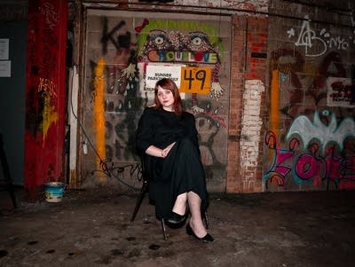 Annie Tammearu sits in a chair in a garage.