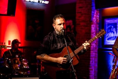 A musician sings and plays guitar onstage