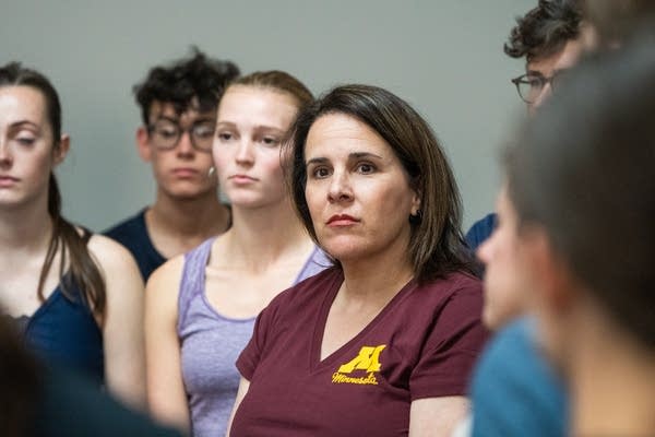 A woman in a maroon shirt listens intently. 