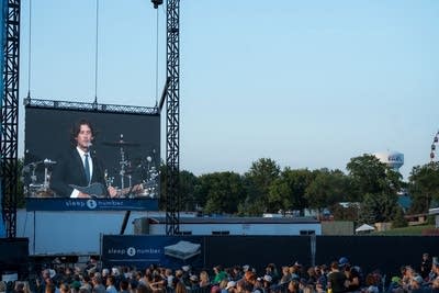 A musician's likeness projected onto a very large screen at an outdoor music venue