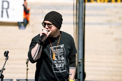 A hip-hop MC performing on an outdoor stage at a large rally