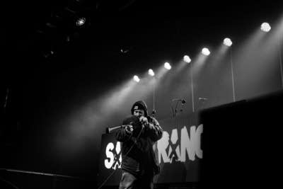 A rapper performs onstage during a show in a music venue