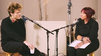 Two people have a conversation in a recording studio