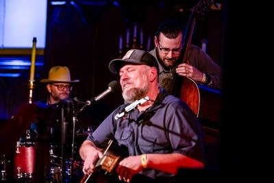 Three musicians perform together onstage