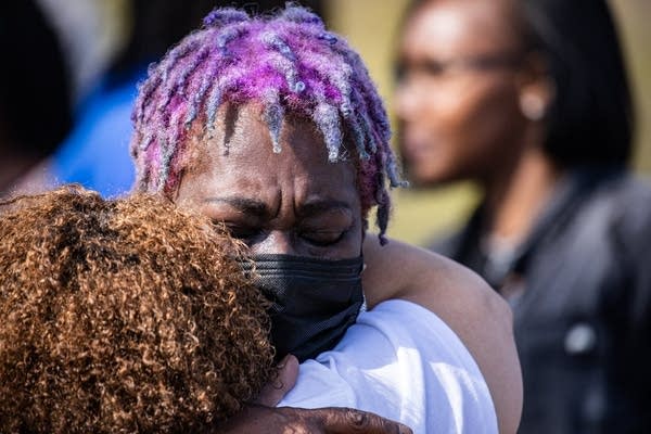 A woman with purple hair gives a hug.