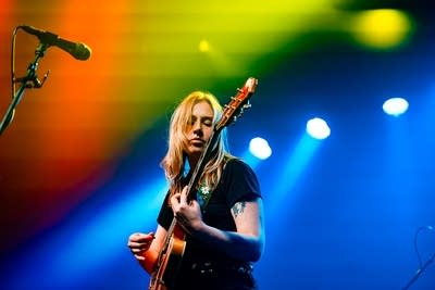 A musician plays guitar onstage in a music venue