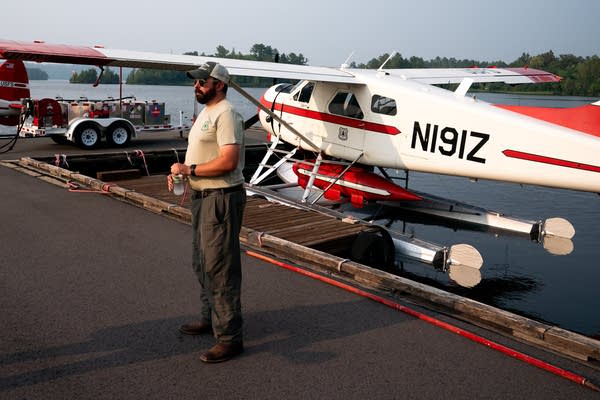 A pilot poses next to a firefighting plane on the water.