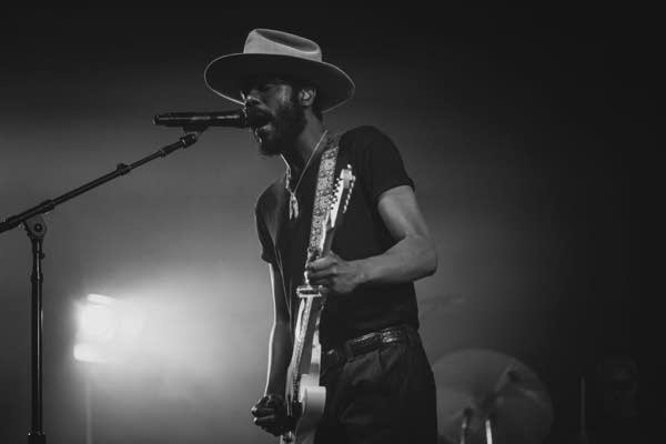 A musician sings and plays guitar in a large music venue